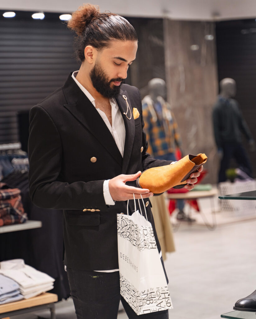 Stylish man in a store, deciding on what to wear on his first date.