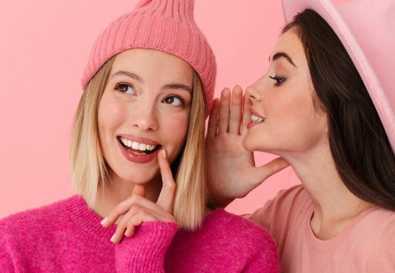 Woman whispering sex coaching myths into friend's ear