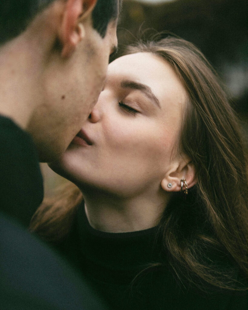 A beautiful woman kisses a young man