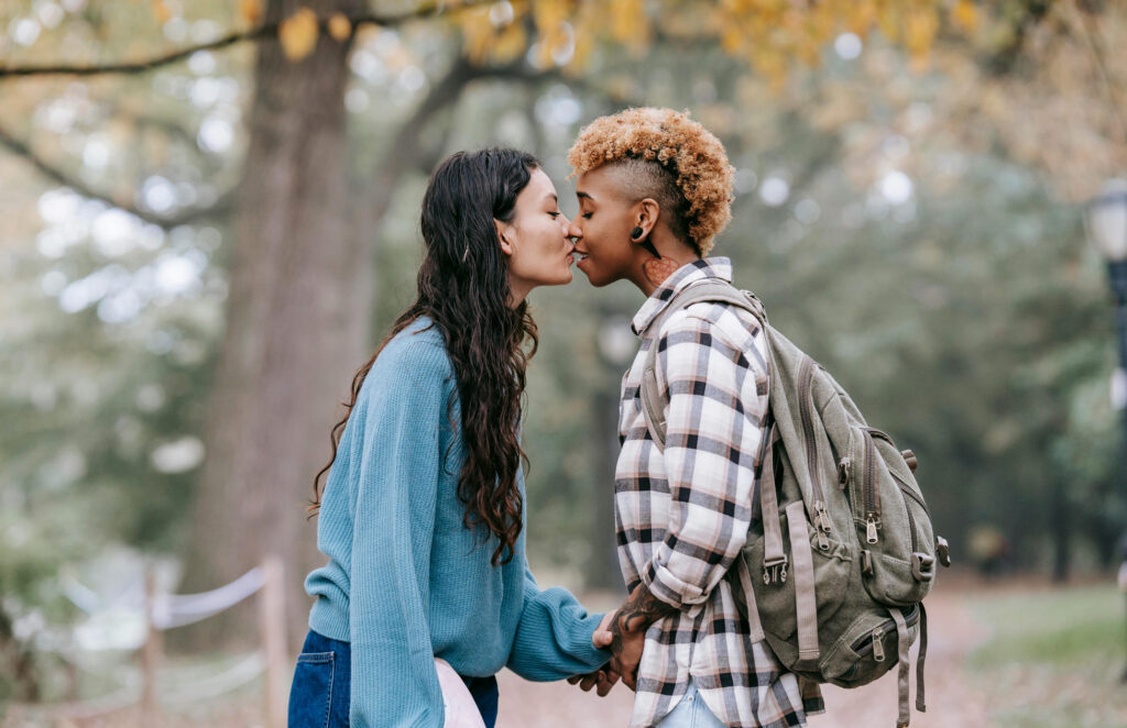 Two women kissing in a park after asking for consent